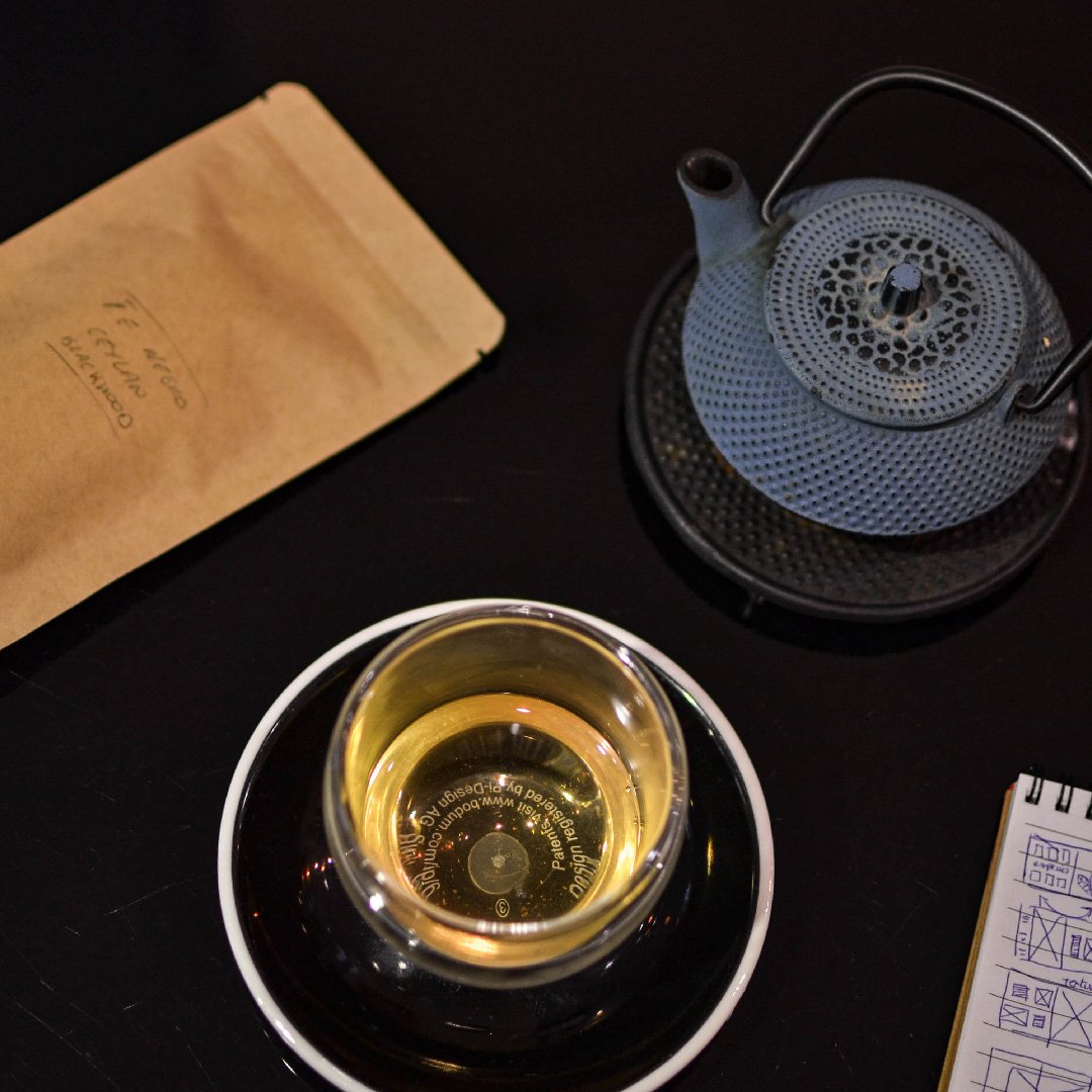 Té en hoja pesado junto a una taza de capacidad media sobre fondo limpio